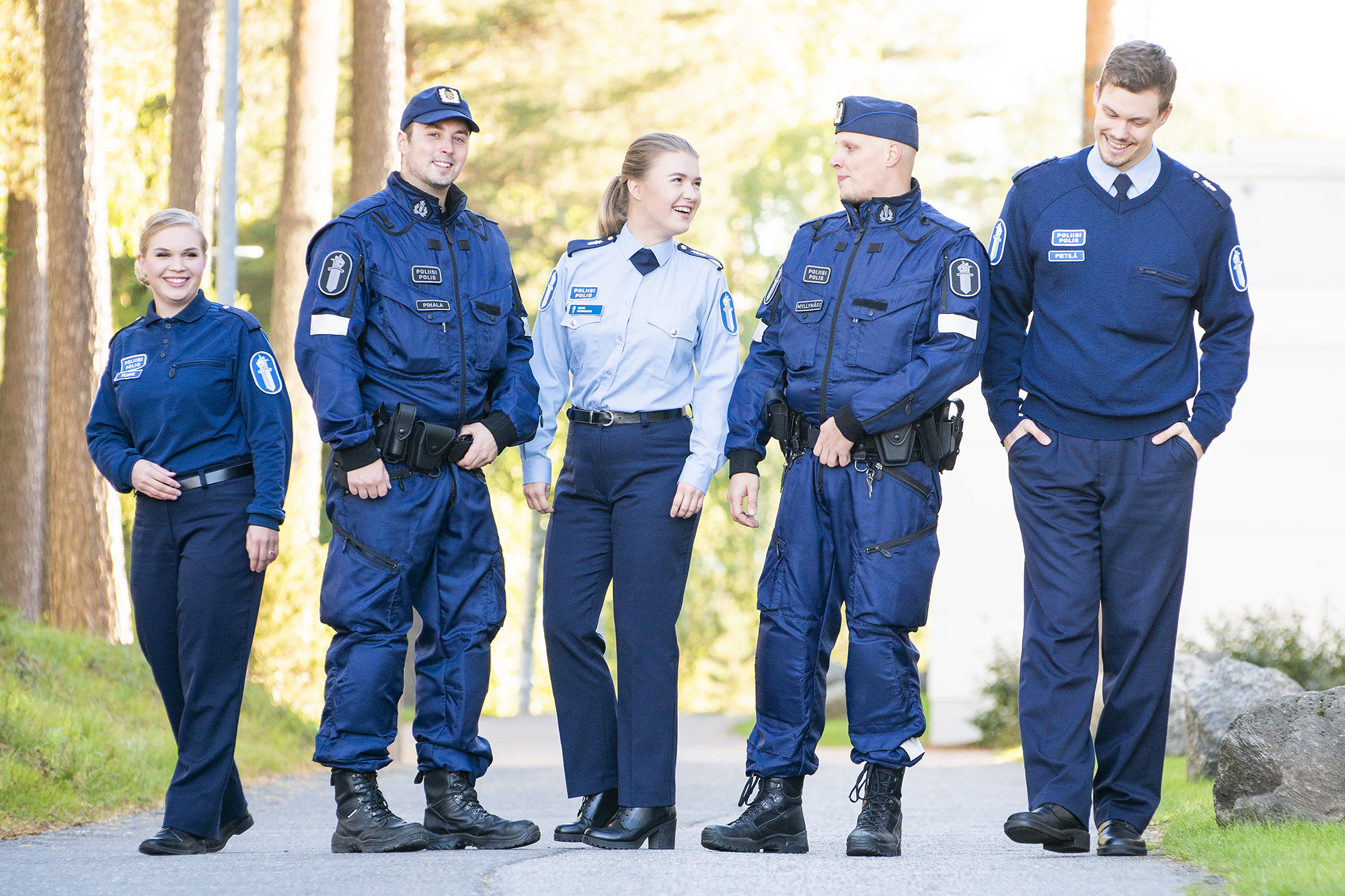 Fem polisstuderande i uniform går sida vid sida utomhus på Polisyrkeshögskolans campus.